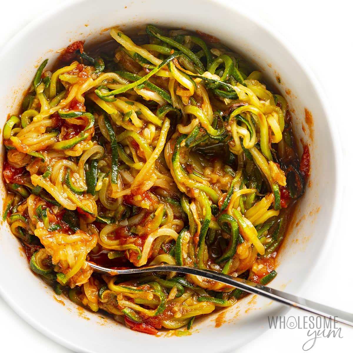Zoodles and sauce mixed in a large bowl.