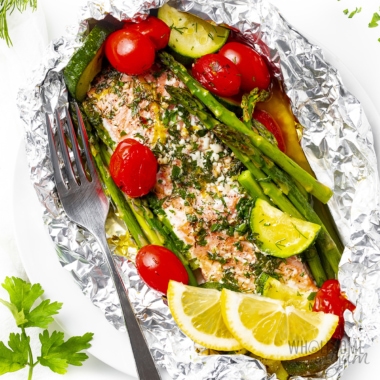 Baked salmon in foil with vegetables and lemon slices.