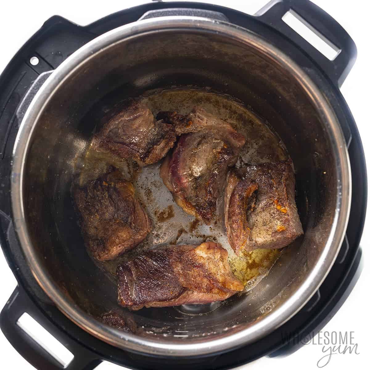 Beef short ribs searing in Instant Pot.