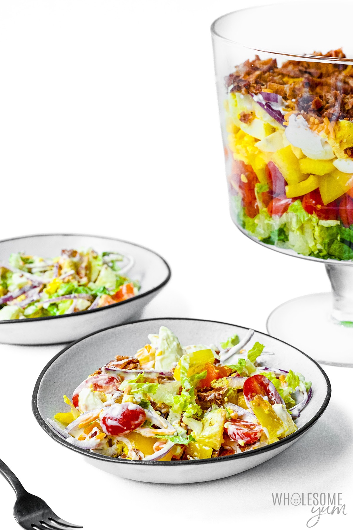 Seven-layer salad with large bowls in the background.