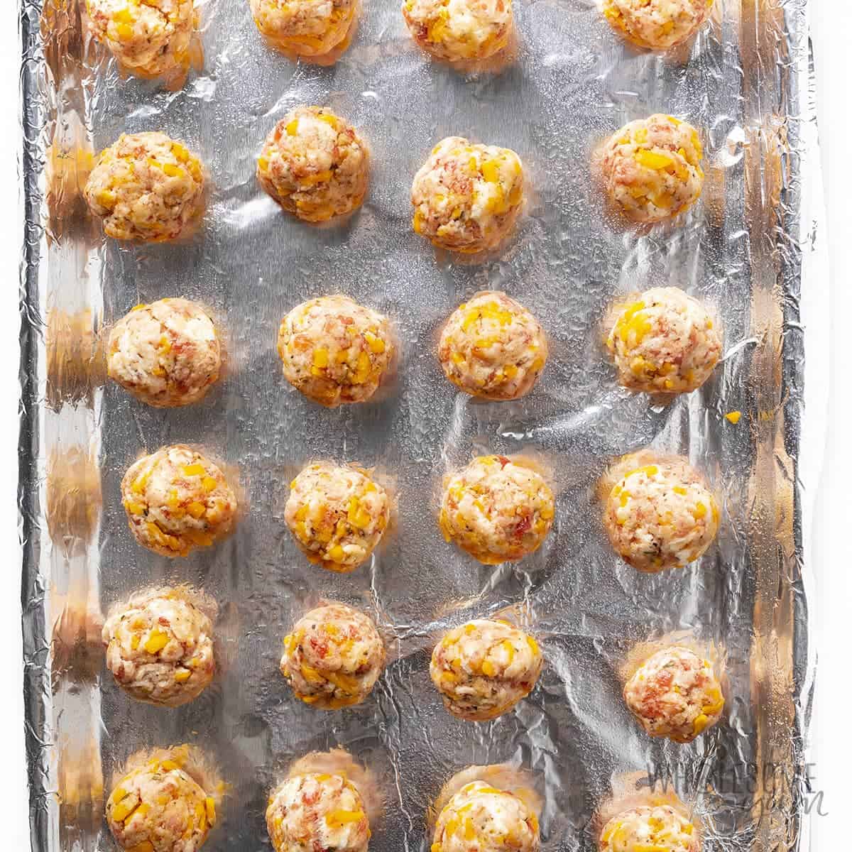 Raw cream cheese sausage balls on a baking sheet.