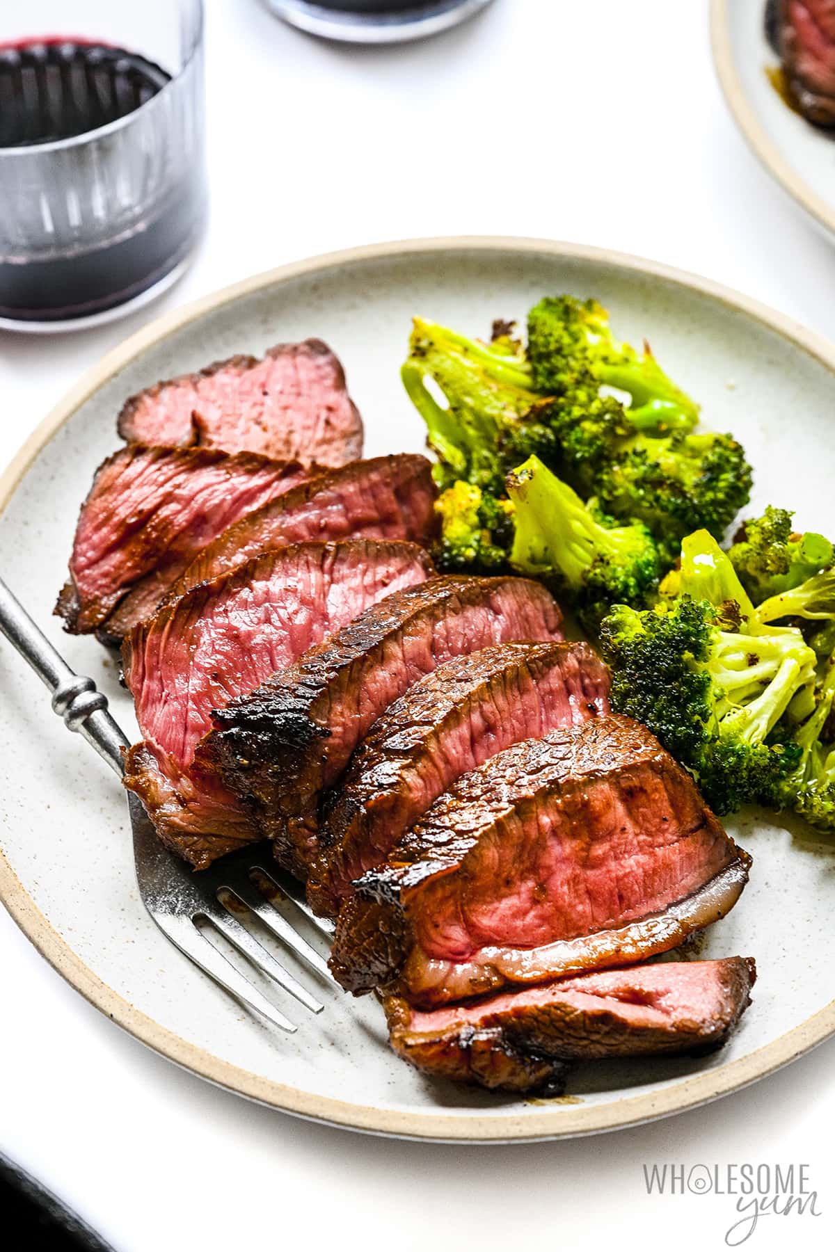 Sliced steak cooked in marinade on a plate with broccoli and a fork.