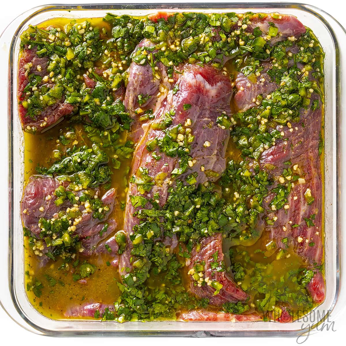 Beef marinating in a baking dish.