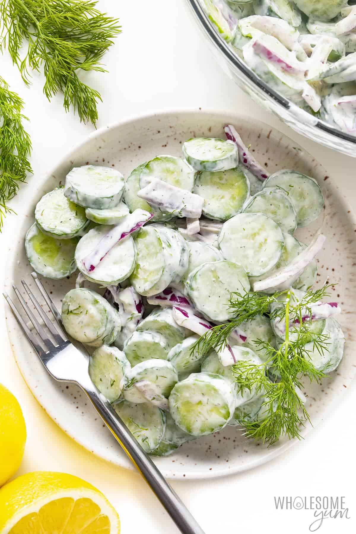 Creamy cucumber salad recipe on a plate with a fork.