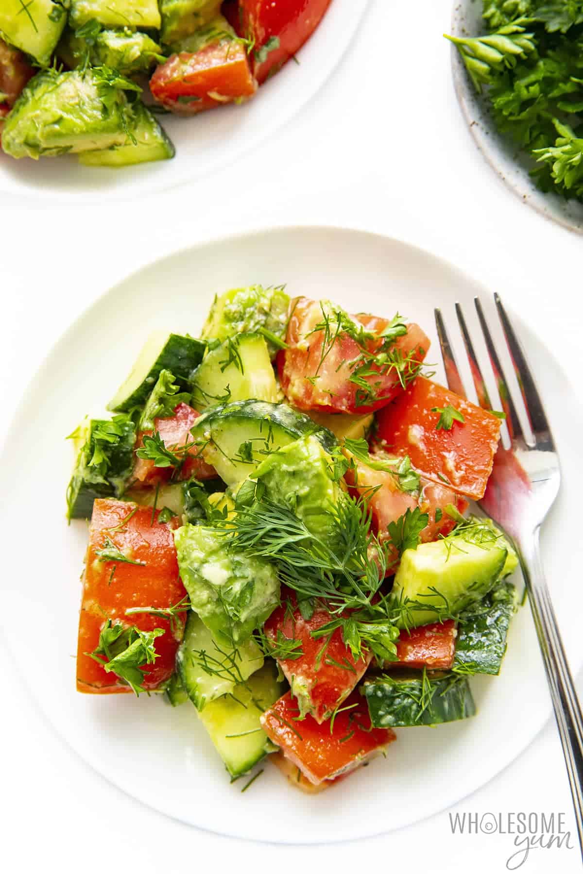 Salad with tomato, cucumber, and avocado on a plate with fork