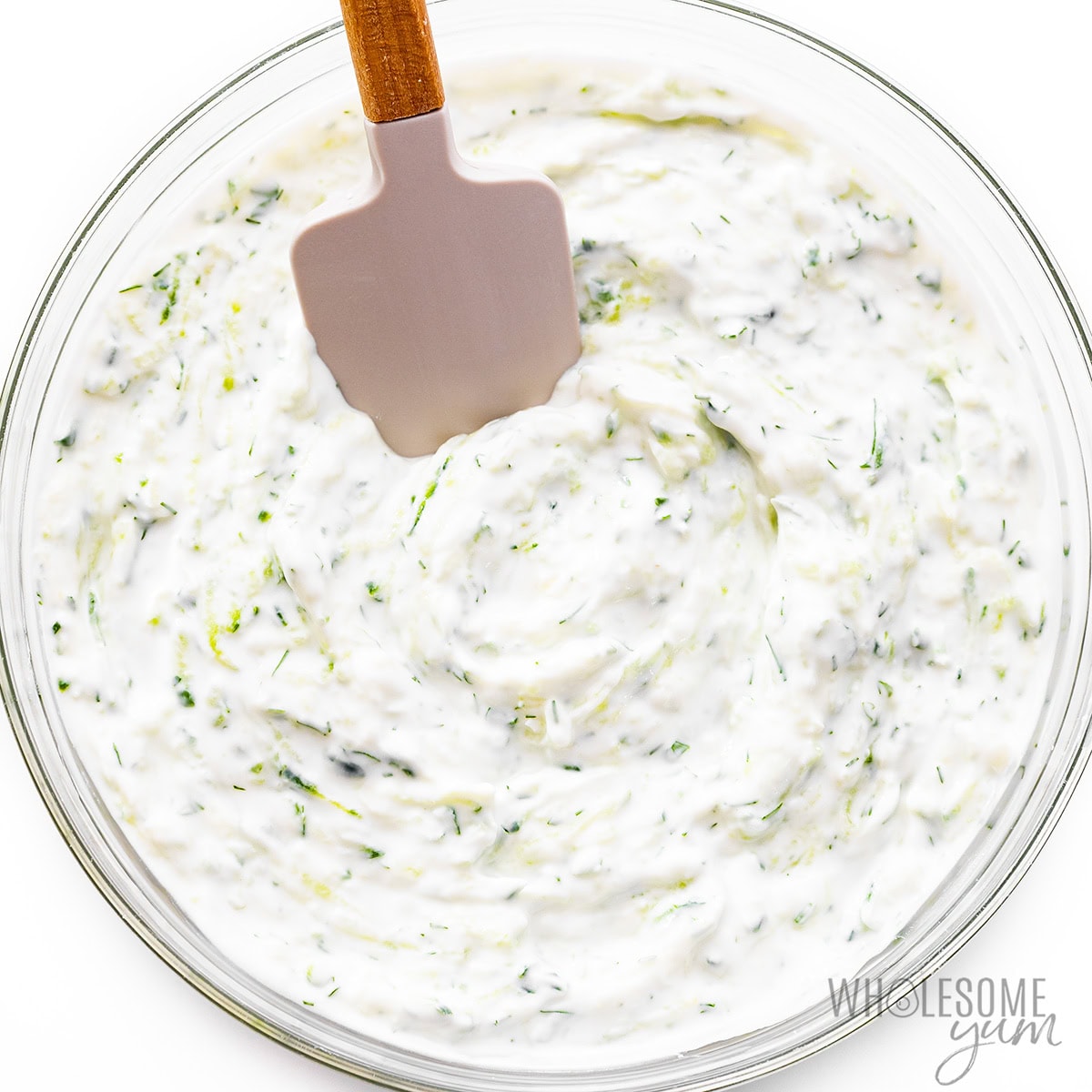 Shredded cucumbers added to yogurt mixture and mixed with a spatula.