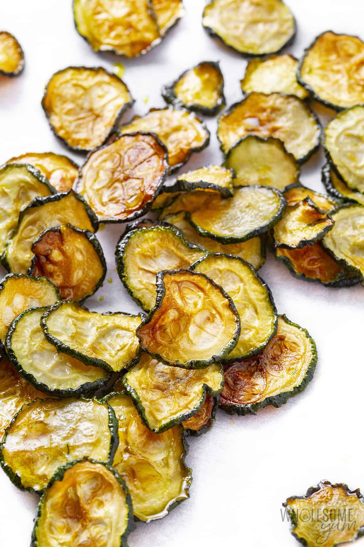 Sprinkled zucchini chips on parchment.