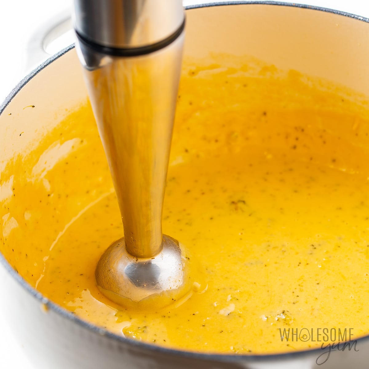 Pureeing broccoli cheddar soup with an immersion blender.