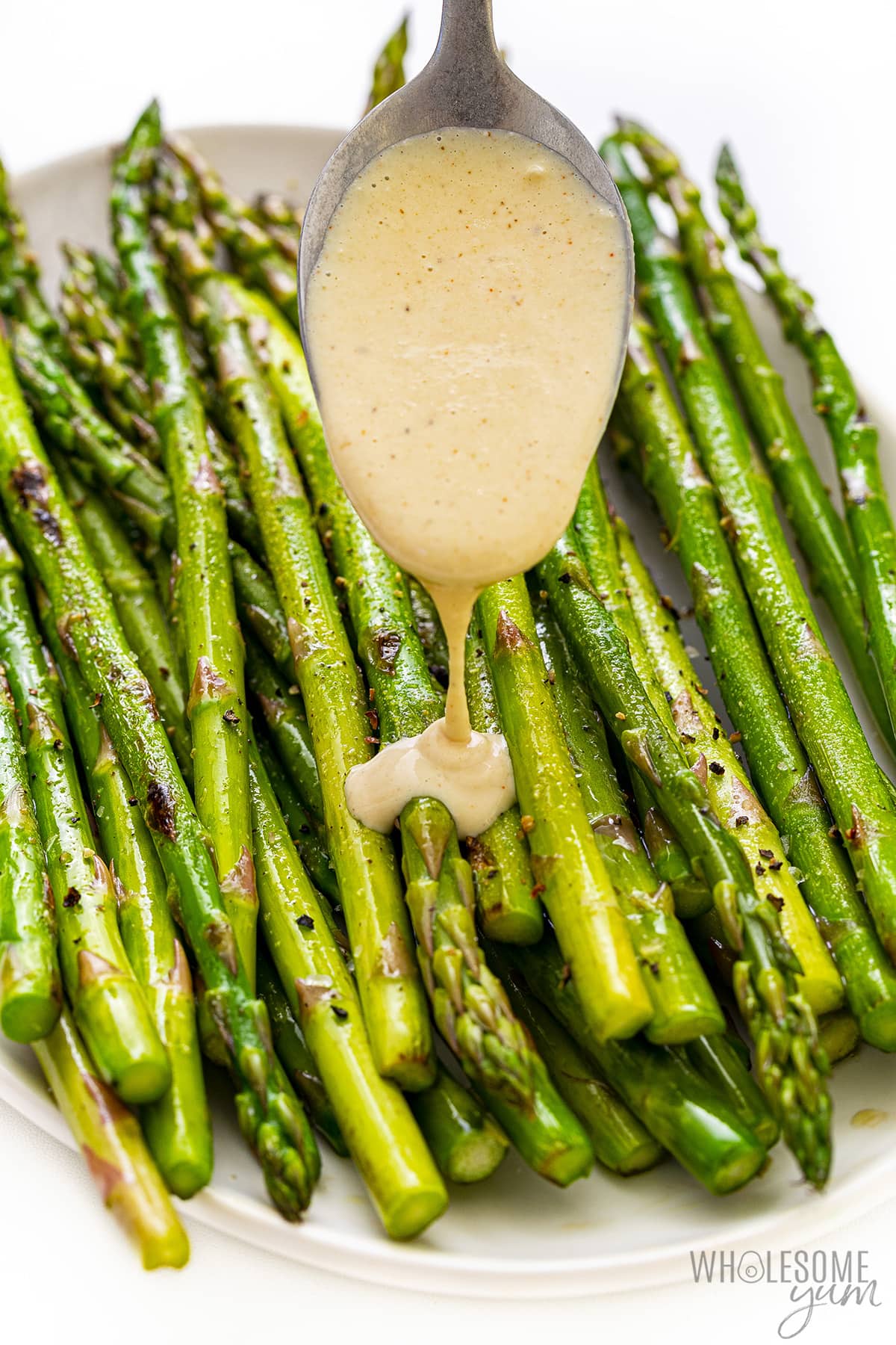 Tahini sauce drizzled on asparagus.