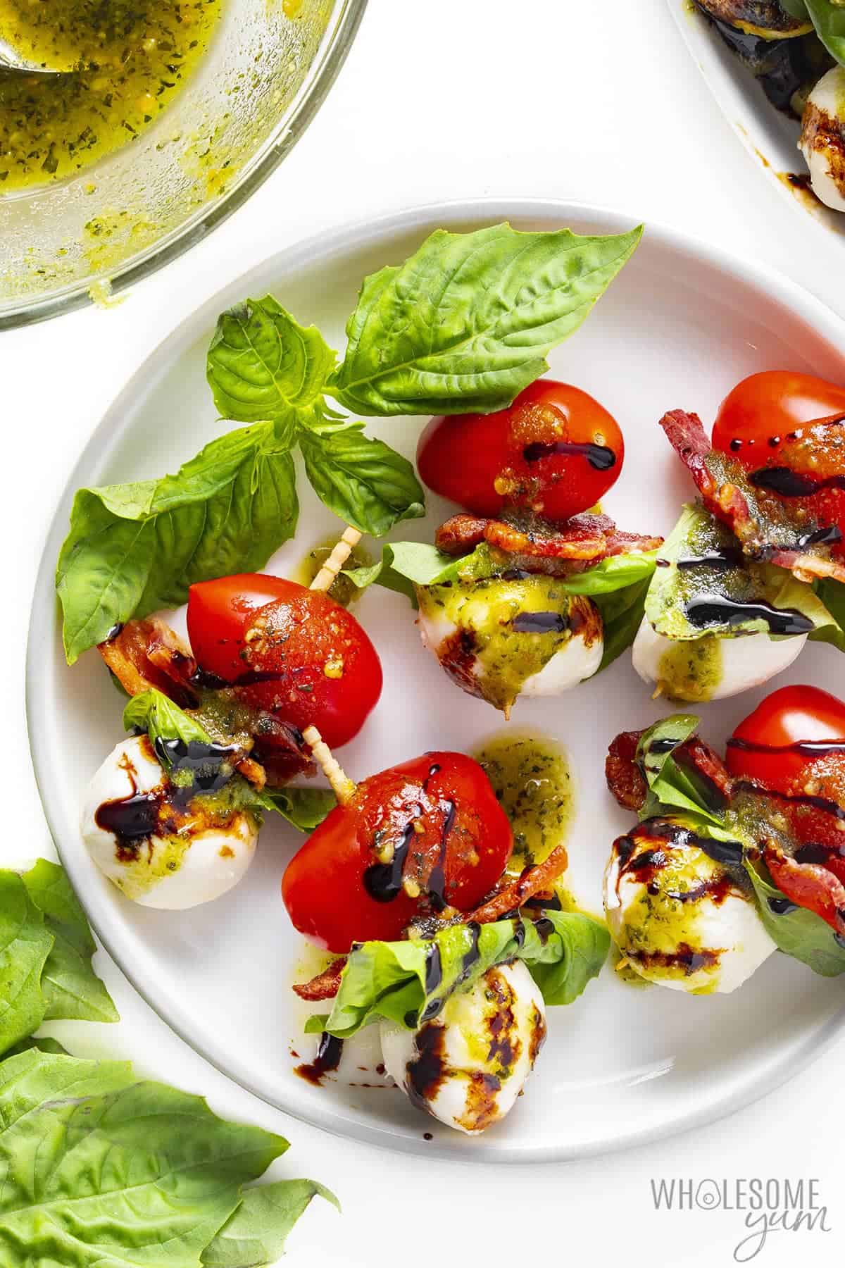 Caprese salad skewers on a plate with balsamic glaze.