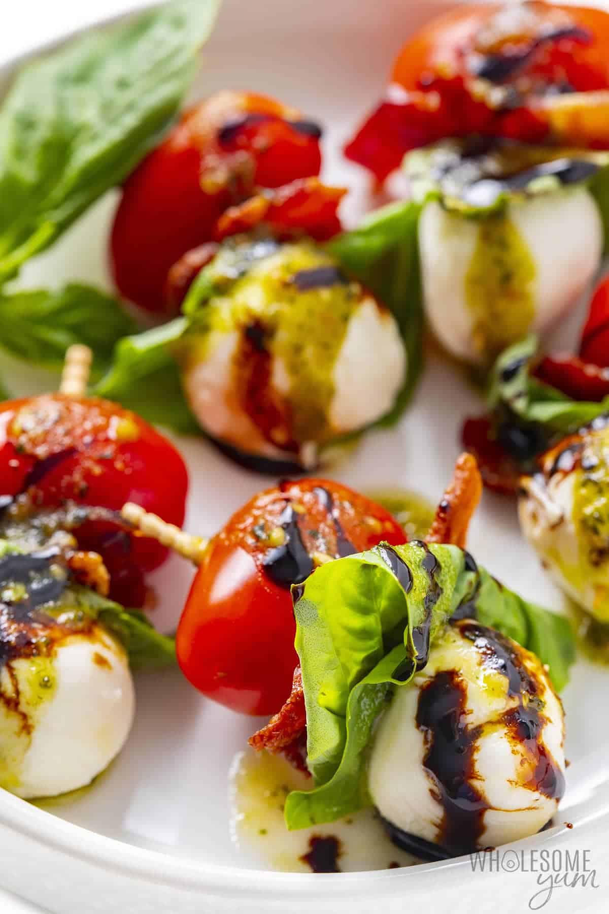 Close up of tomato mozzarella basil skewers on a plate.