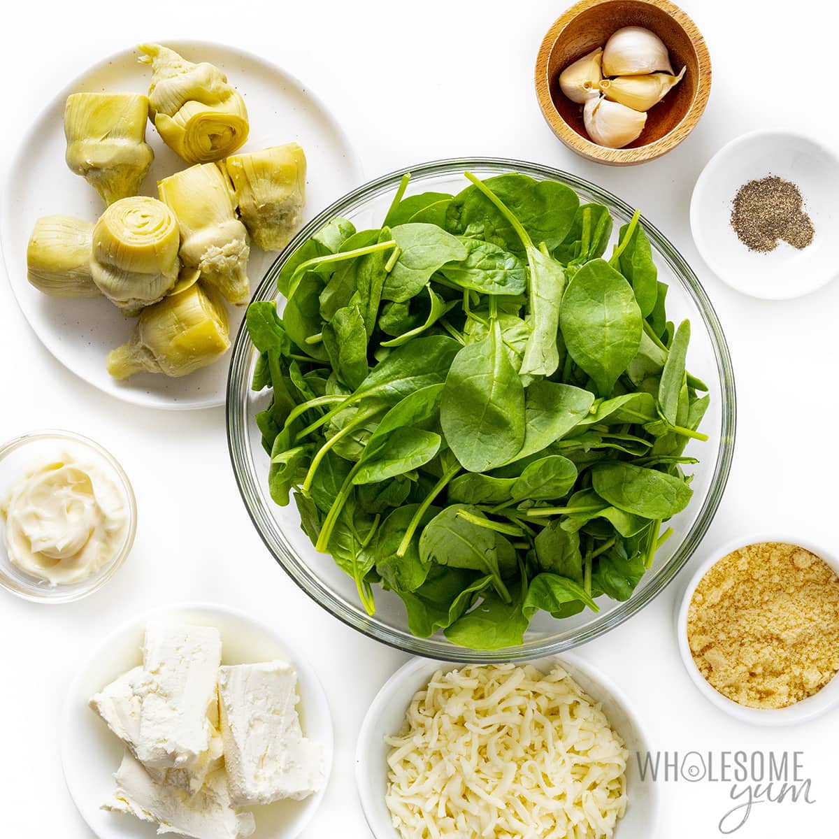 Ingredients for spinach artichoke dip in bowls.