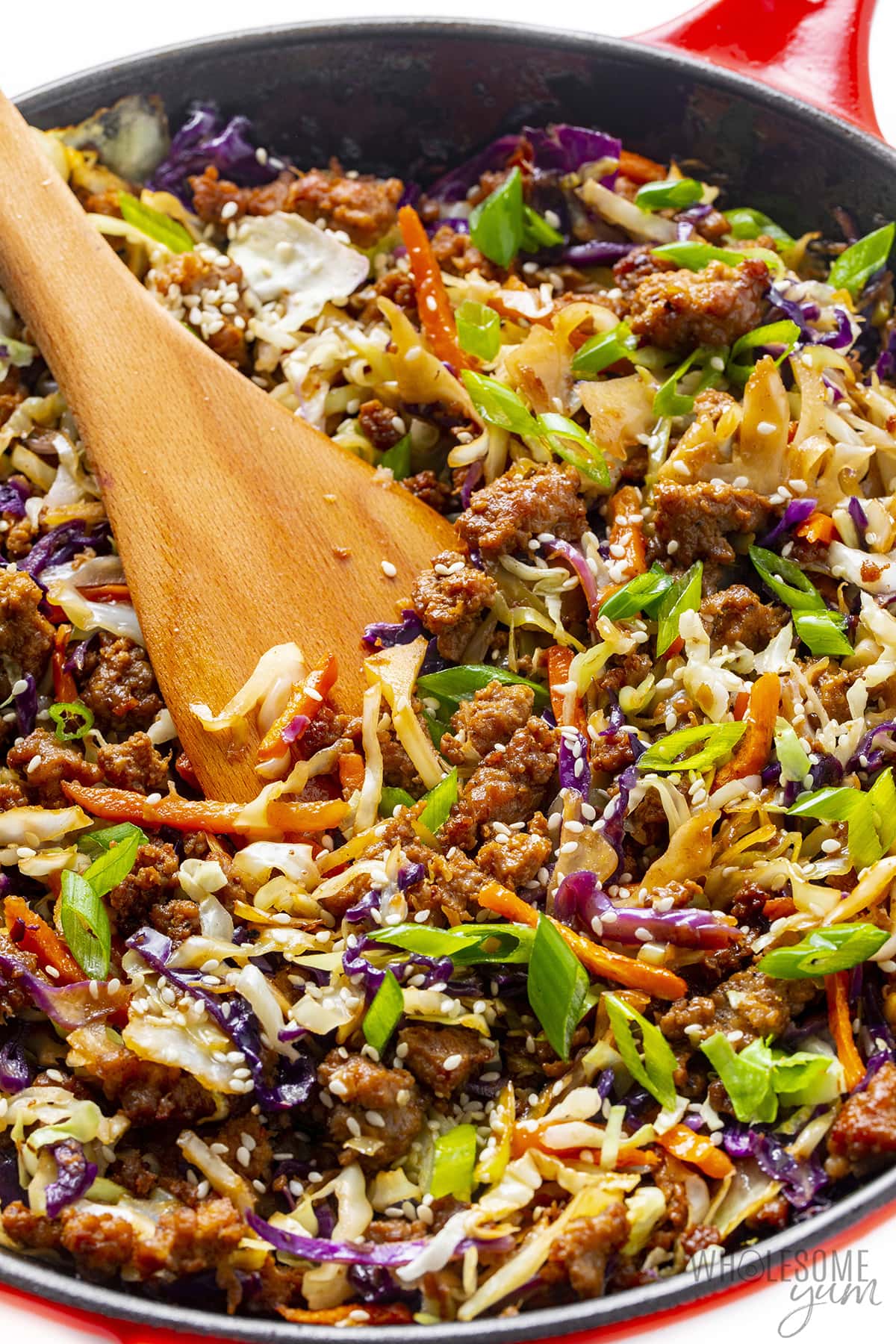 Egg roll bowl stir fry in a skillet with wooden spatula.