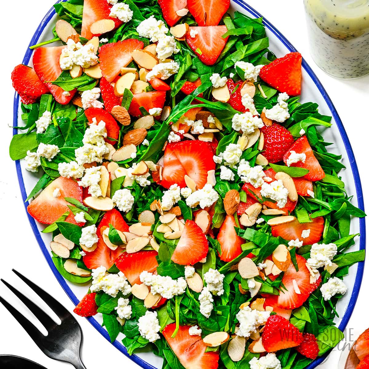Spinach, strawberries, goat cheese, and almonds on a platter.