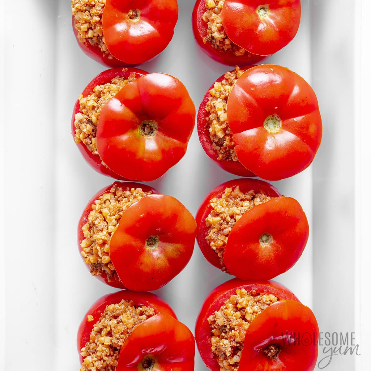 Tomato lids placed on top of stuffed tomatoes.
