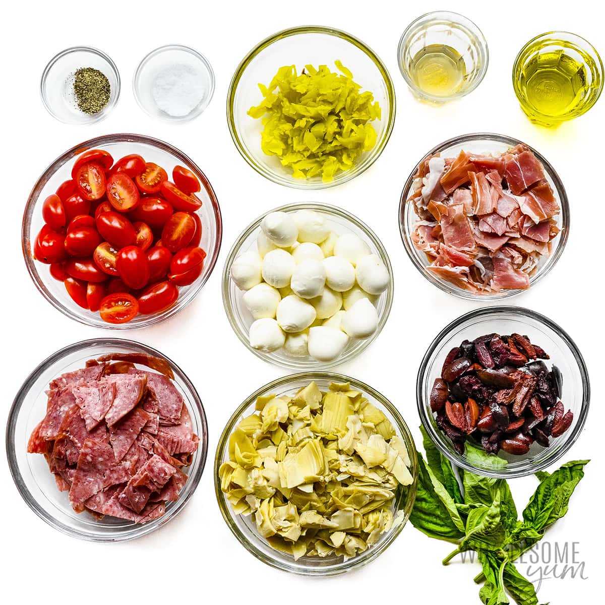 Antipasto salad recipe ingredients measured out in bowls.