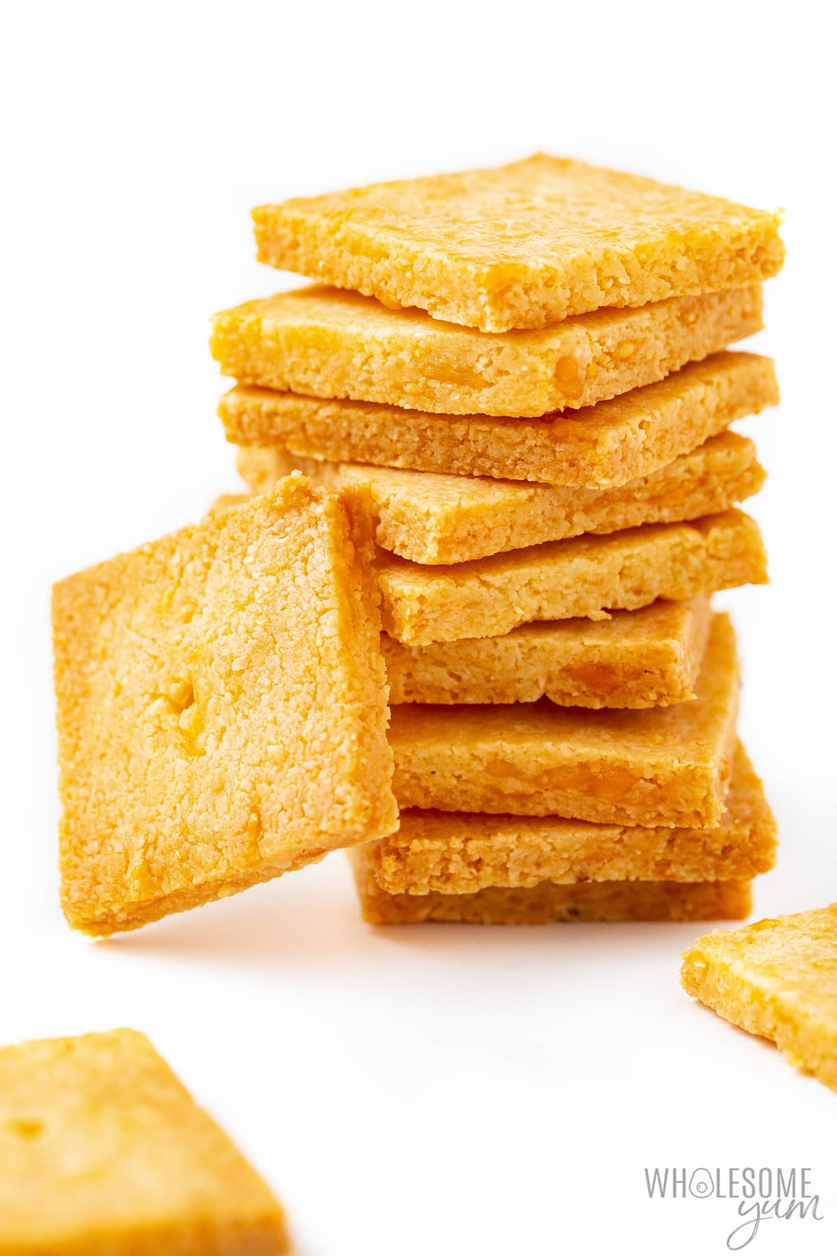 Cheese crackers stacked with others laying beside the stack.