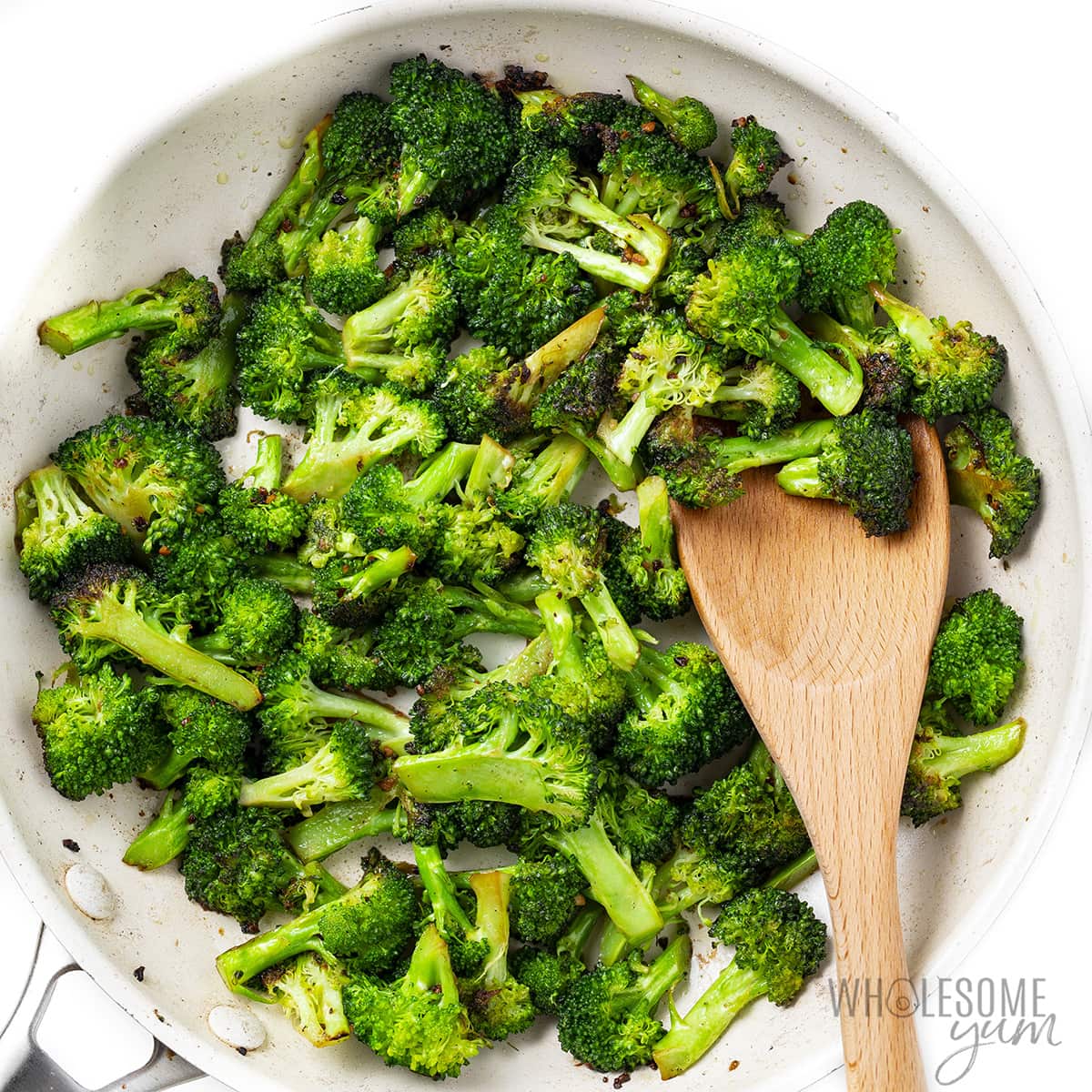 Use a wooden spoon to sauté broccoli in skillet.