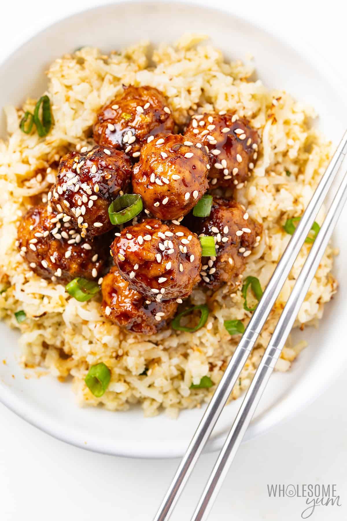 Juicy Asian turkey meatballs served over a base with chopsticks.