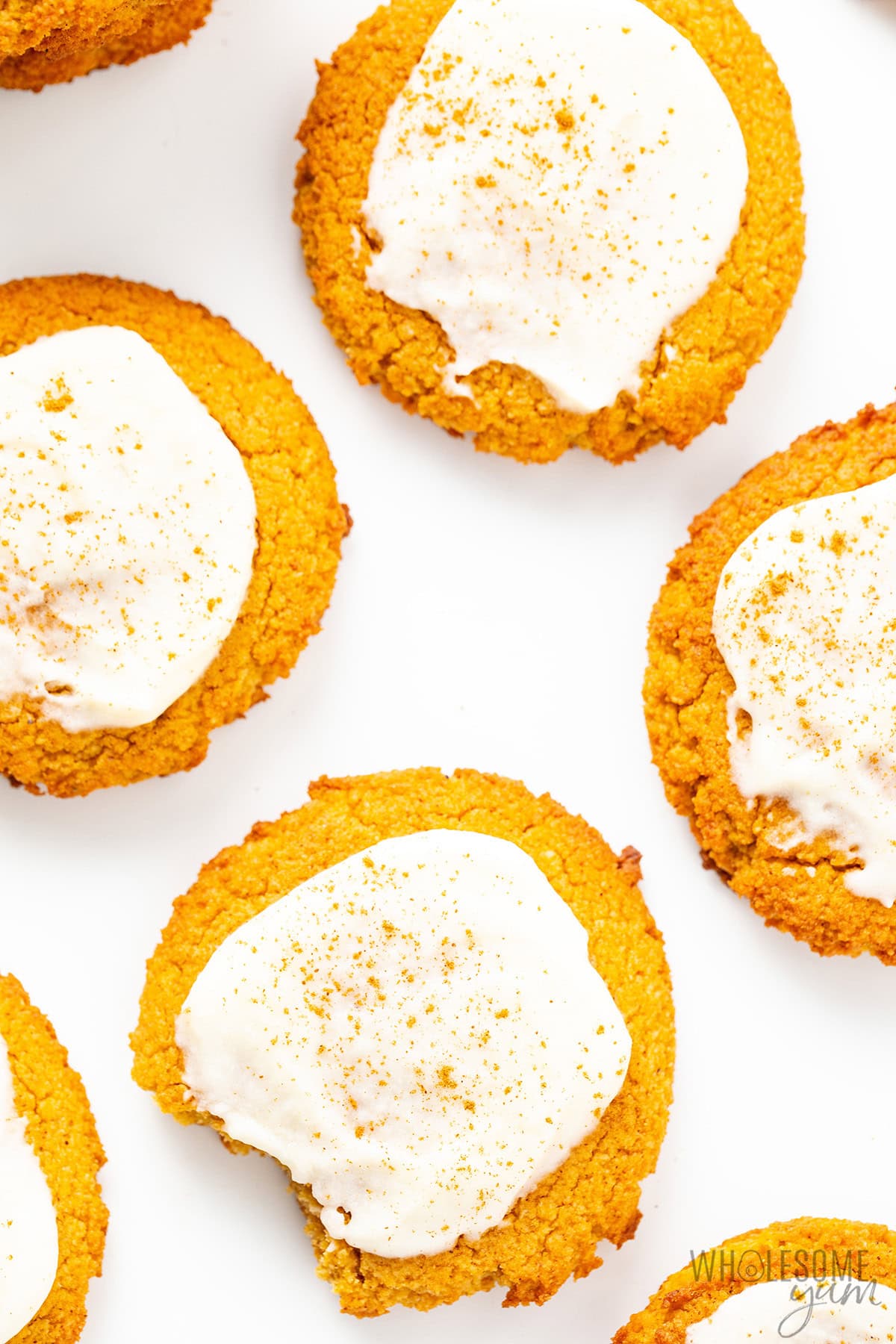 Soft healthy pumpkin cookies topped with vanilla glaze on a pan.