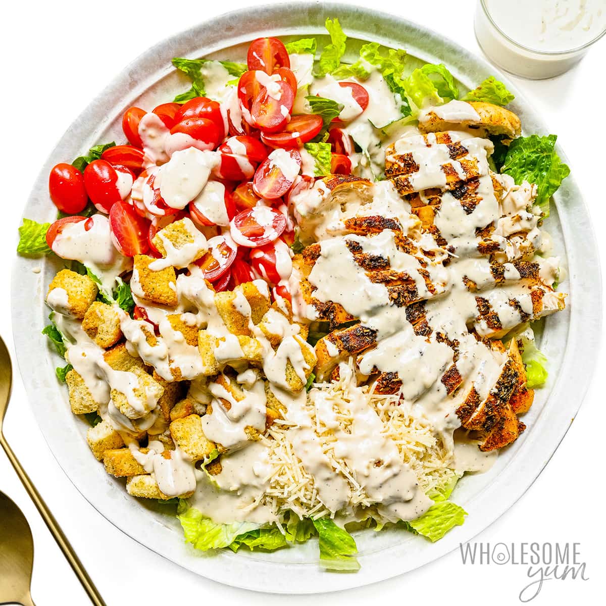 Chicken caesar salad on a plate with dressing.