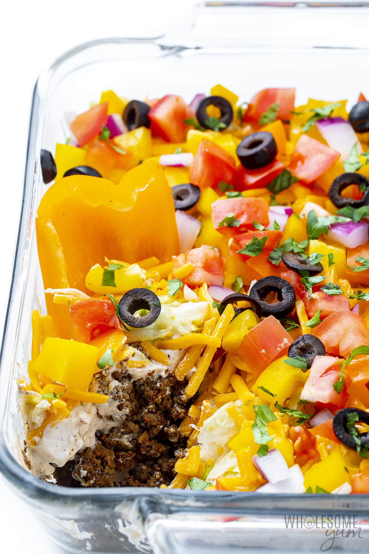 7 layer taco dip in clear dish with bell pepper scoop.