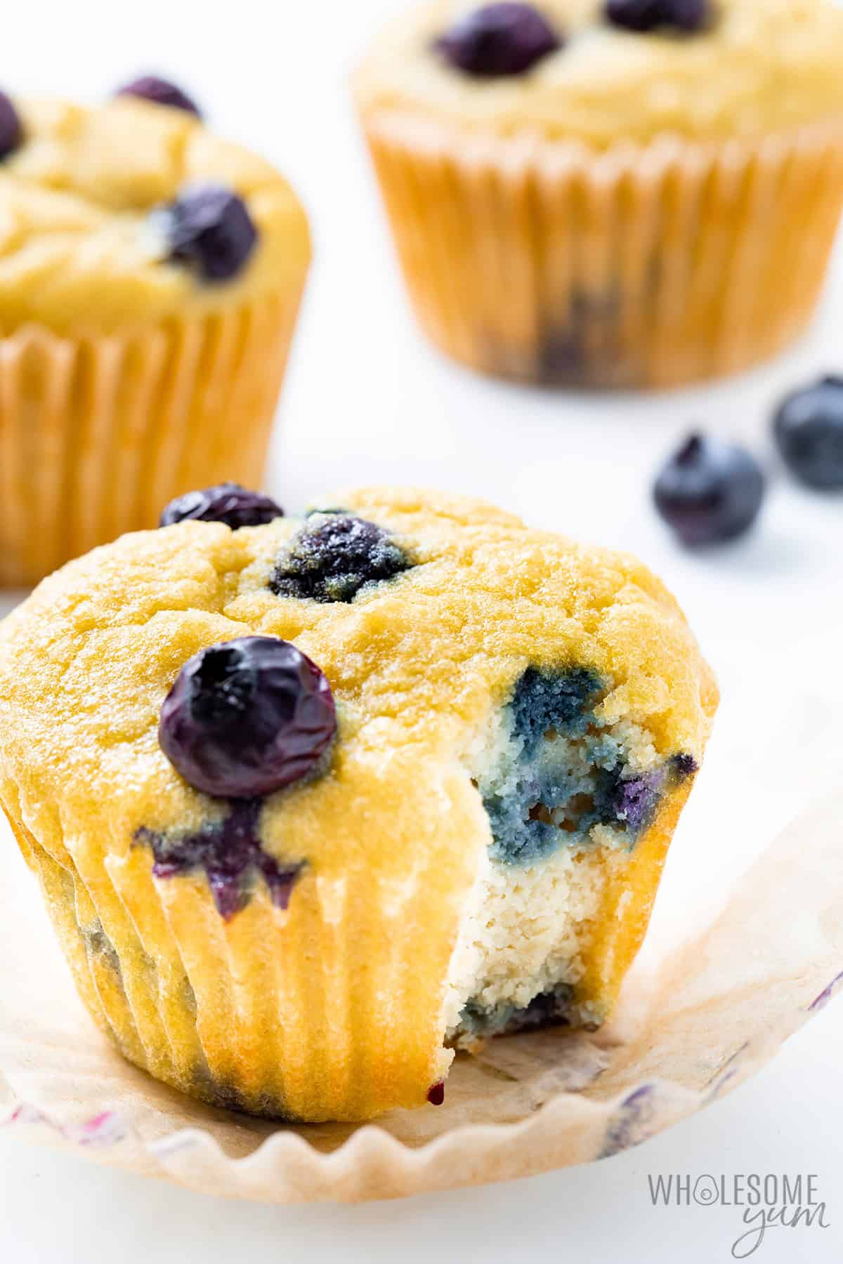 Fluffy bakery-style coconut flour muffins with juicy blueberries and a bite taken out.