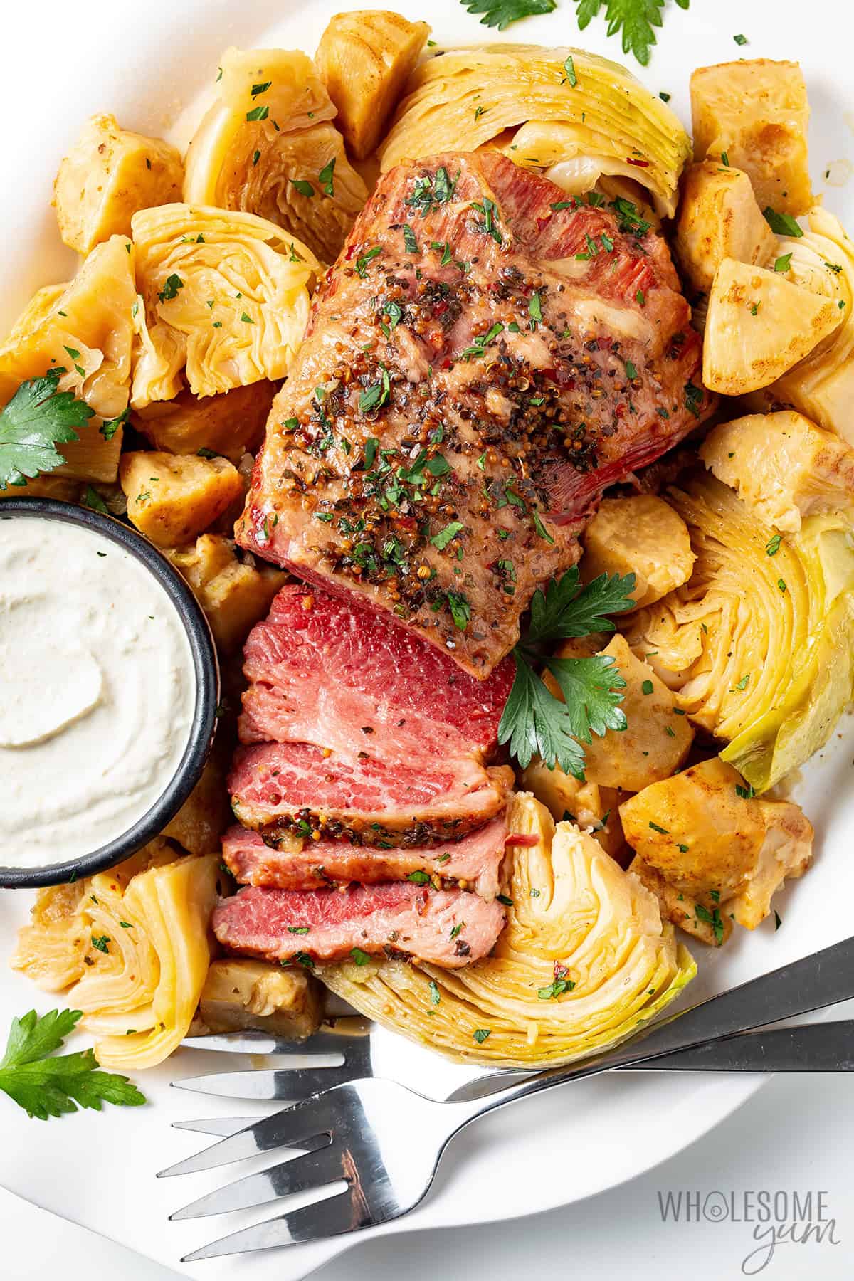 Tender Instant Pot corned beef, cabbage, and celery root on a plate with horseradish sauce.