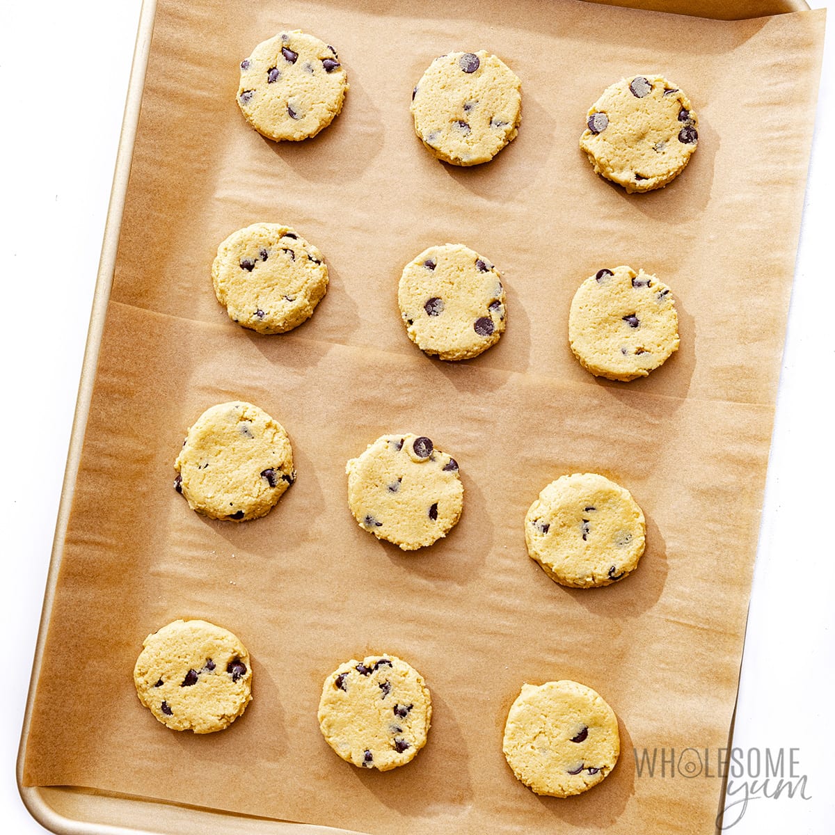 Flattened cookies on a baking sheet before baking.