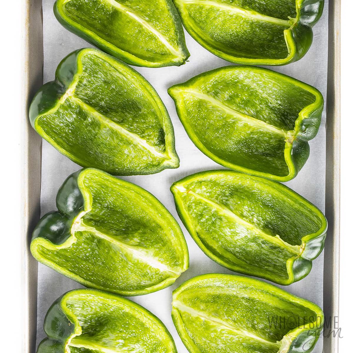 Halved poblano peppers on a baking sheet.