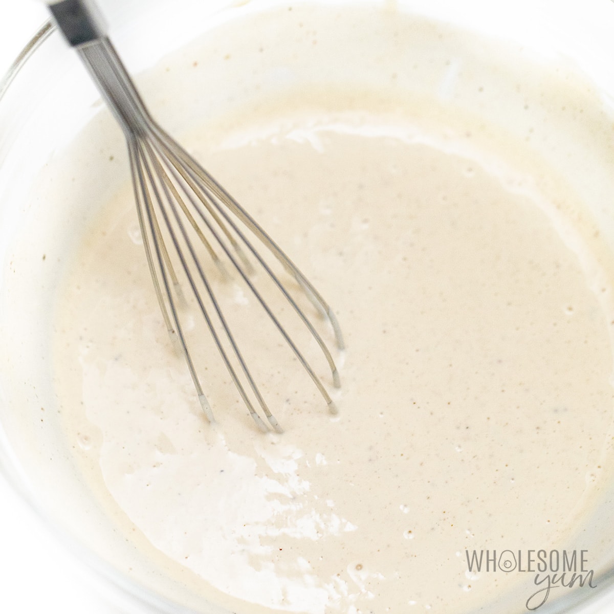 Caesar salad dressing recipe ingredients whisked together in a bowl.