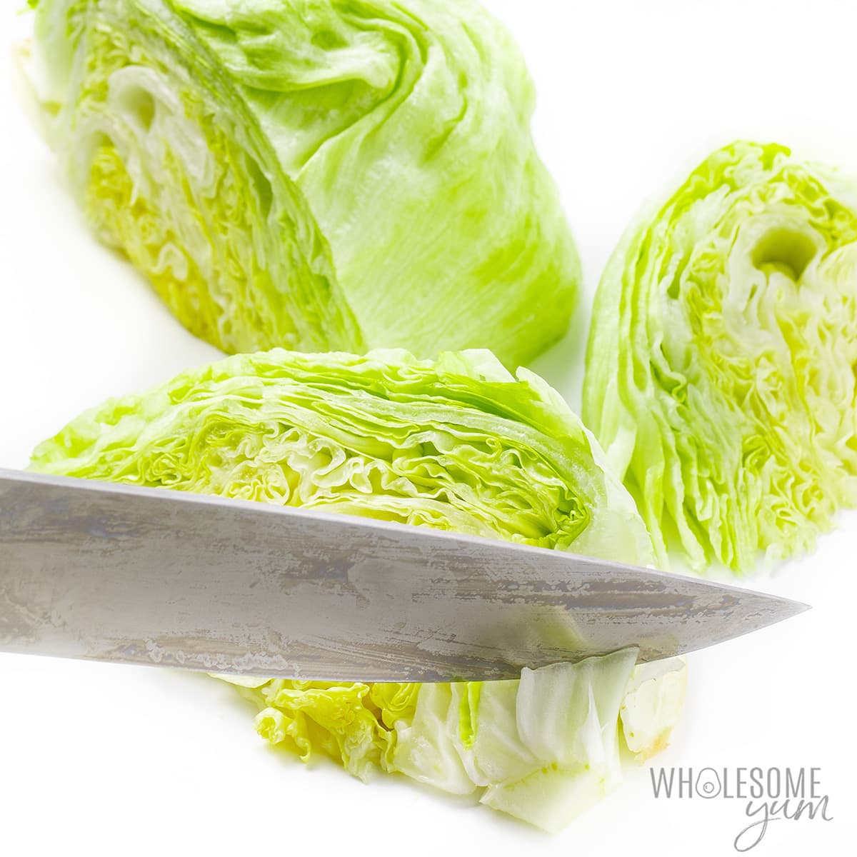 Cutting iceberg lettuce into wedges with a knife.
