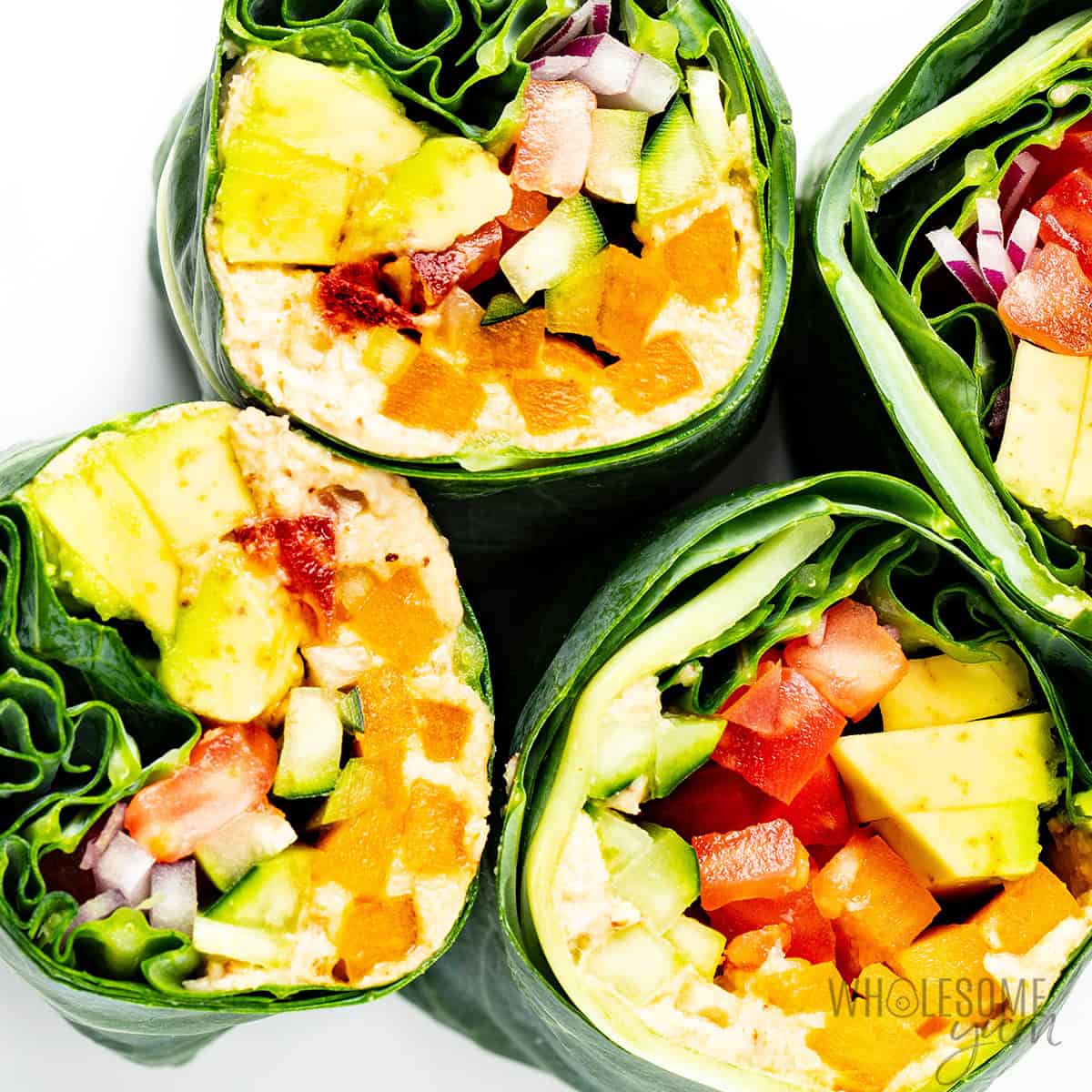 Finished collard green wraps cut in half to show the fillings inside.