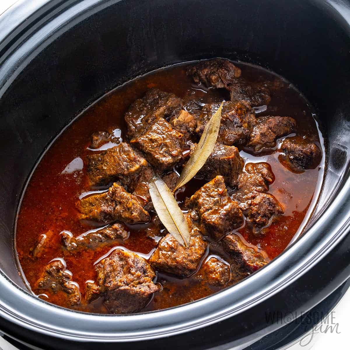 Cooked beef and sauce in slow cooker, before shredding.