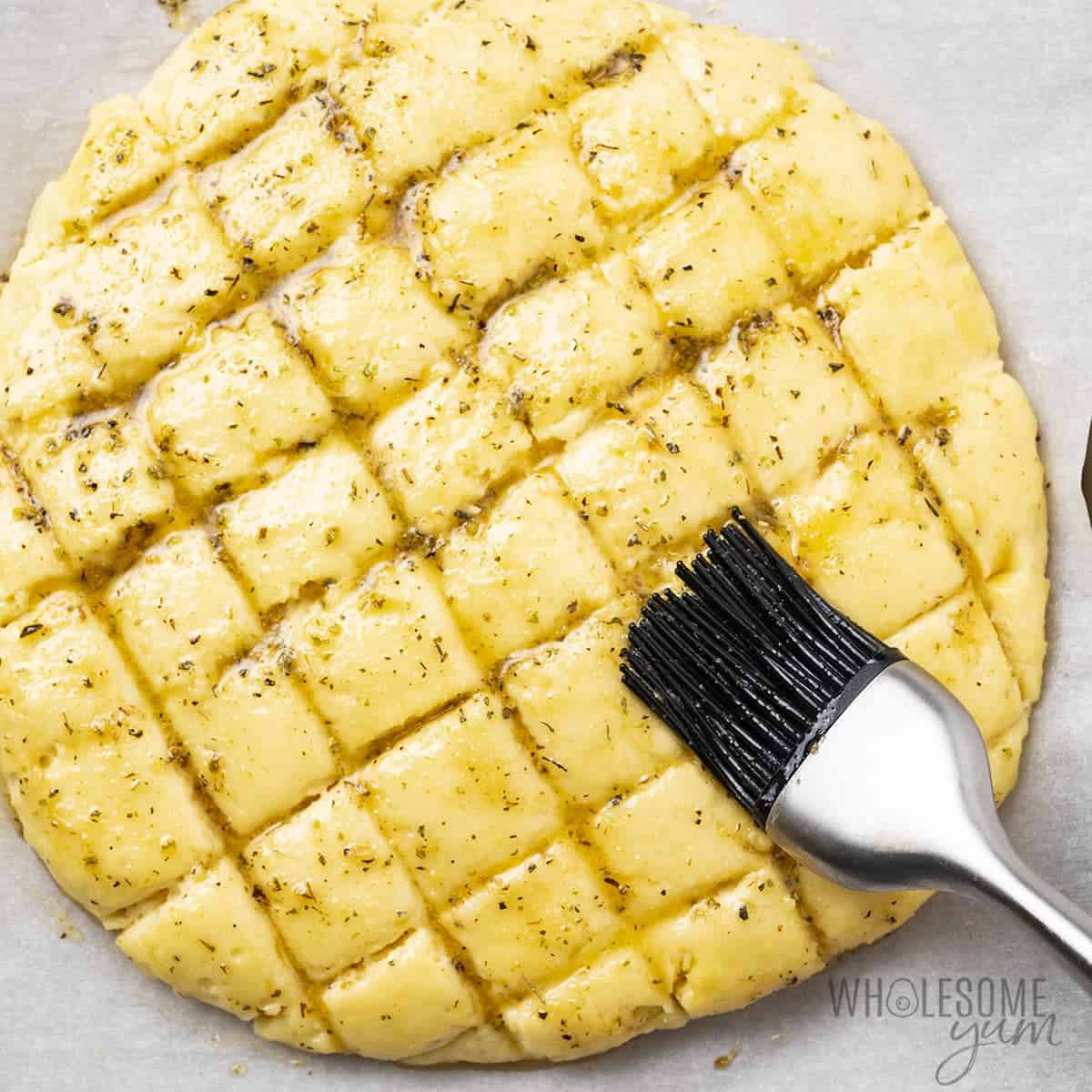 Brushing low carb cheese bread with garlic butter.