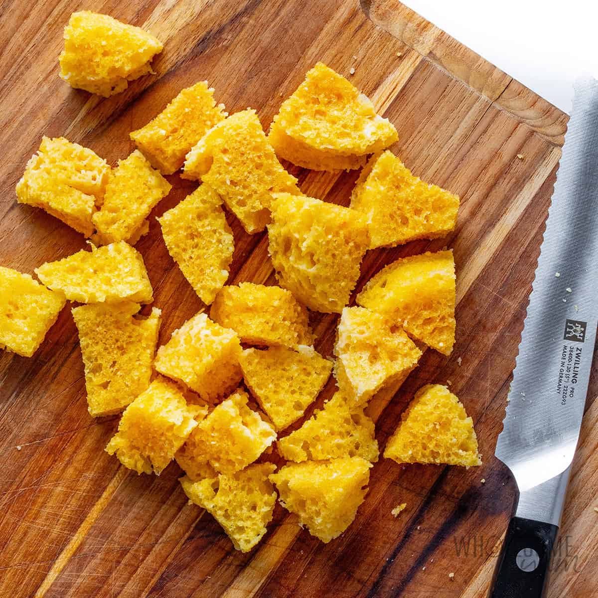 Cutting cake into cubes on a cutting board.