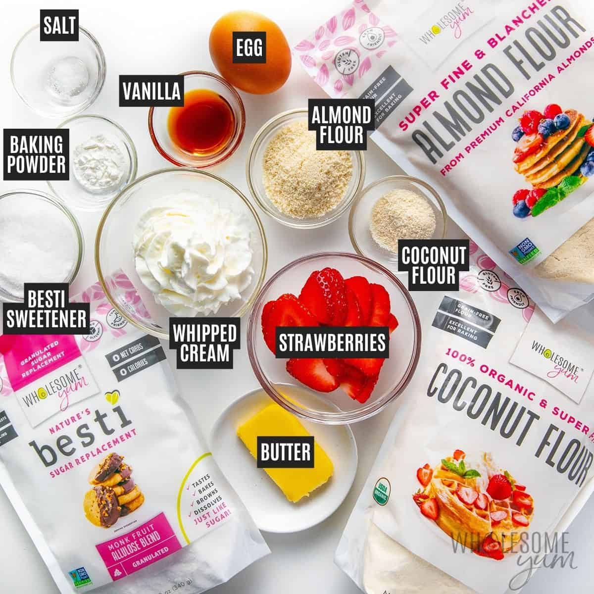 Labeled recipe ingredients: Strawberries, Wholesome Yum Blanched Almond Flour, Wholesome Yum Coconut Flour, Besti Monk Fruit Allulose Blend, unsalted butter, baking powder, vanilla extract, egg, sugar-free whipped cream, and sea salt.