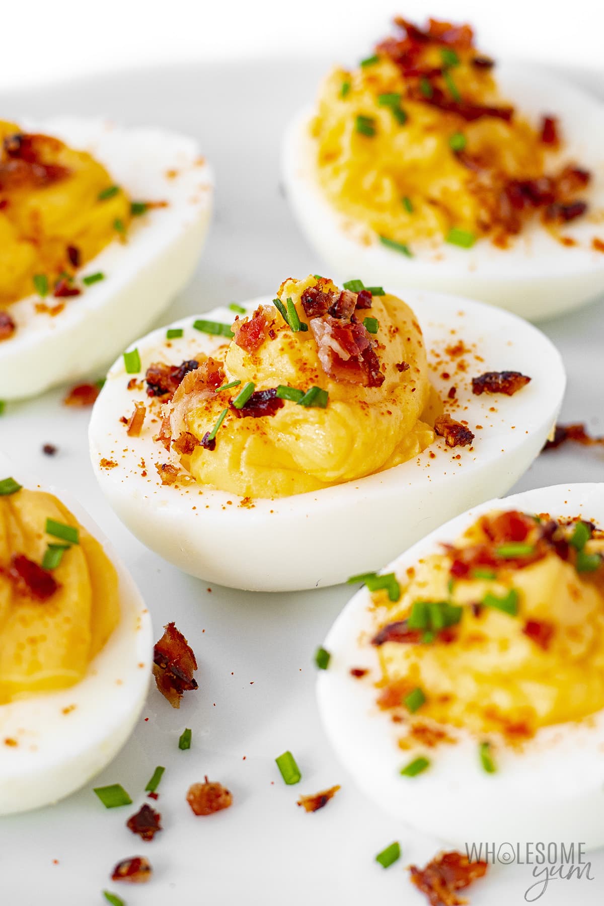 Deviled eggs on a plate with bacon bits and parsley.