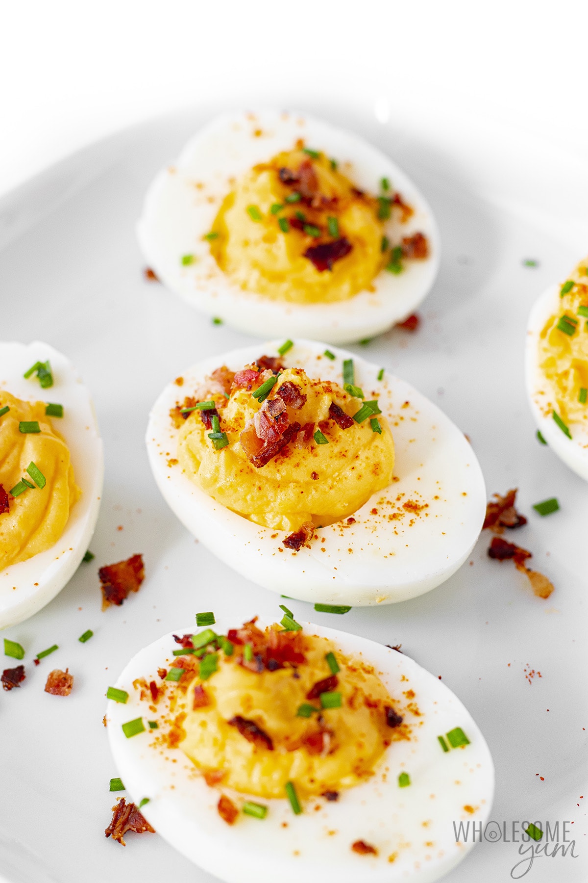 Bacon deviled eggs in a line on a plate.