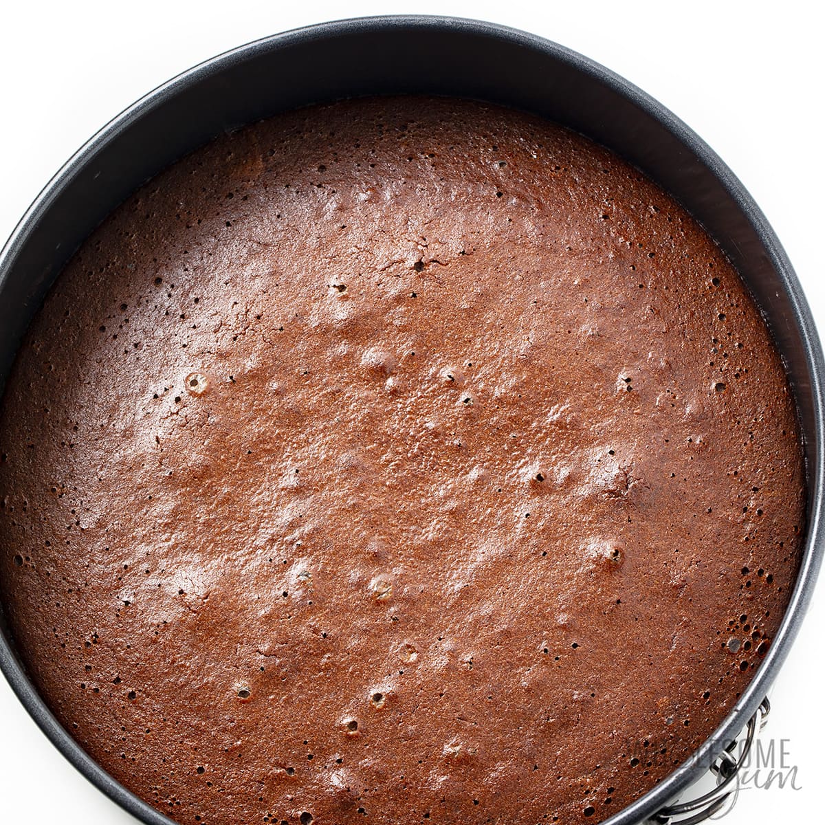 Baked keto chocolate cake in round baking pan.