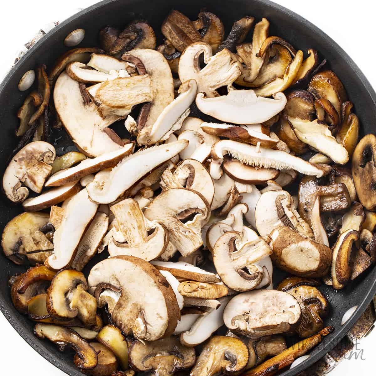 Adding second batch of mushrooms to the pan.