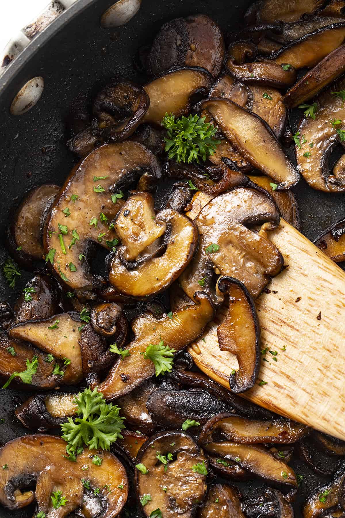 Sauteed mushrooms with butter and wooden spatula.