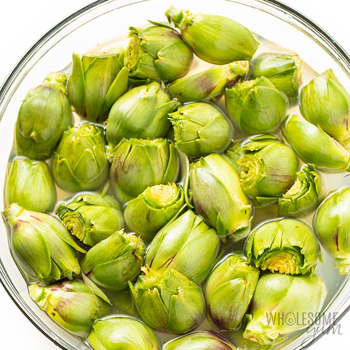 baby artichokes in a large bowl of lemon water