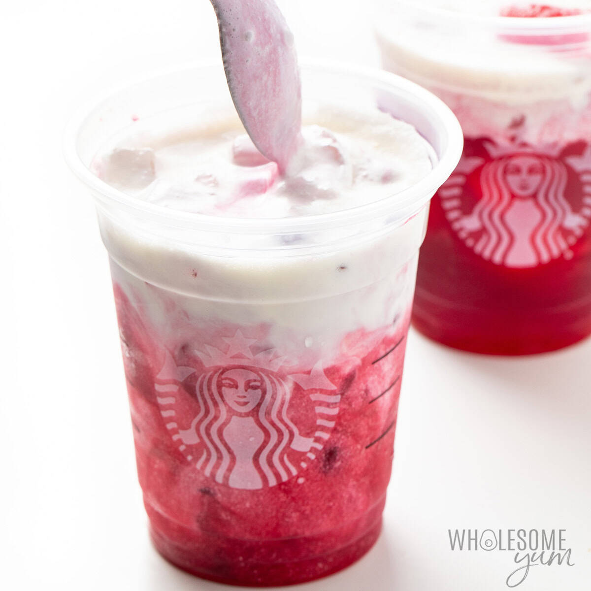 Stirring pink drink ingredients in a cup after combining with the milk.