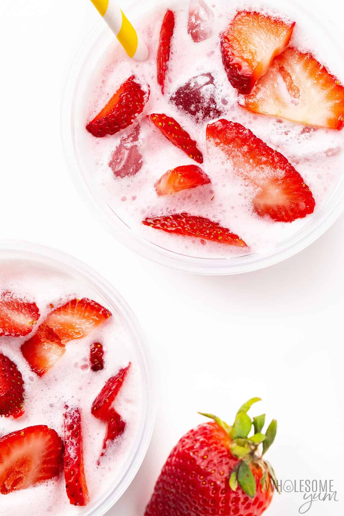 Frothy, creamy pink drink viewed from above, topped with sliced strawberries.