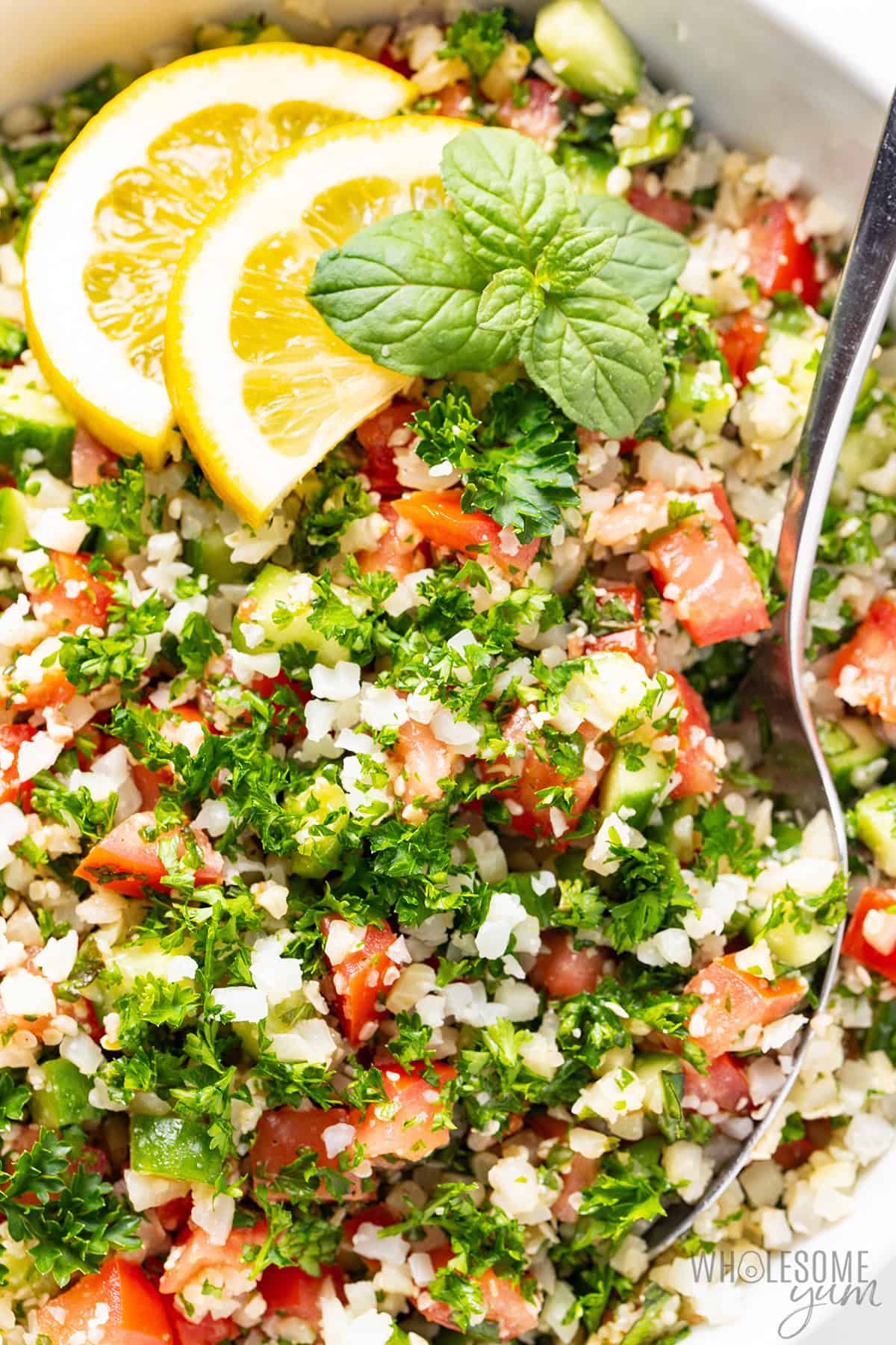 Cauliflower tabbouleh with parsley, tomatoes, cucumber, mint, and lemon dressing in a bowl.