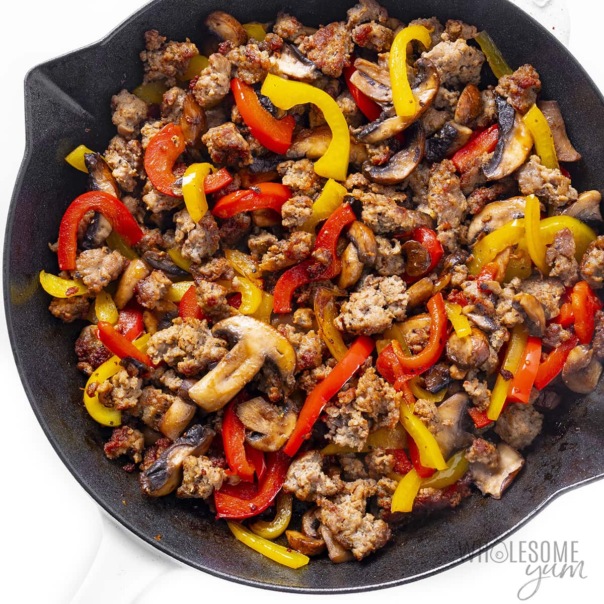 Sauteed veggies and sausage in a skillet.