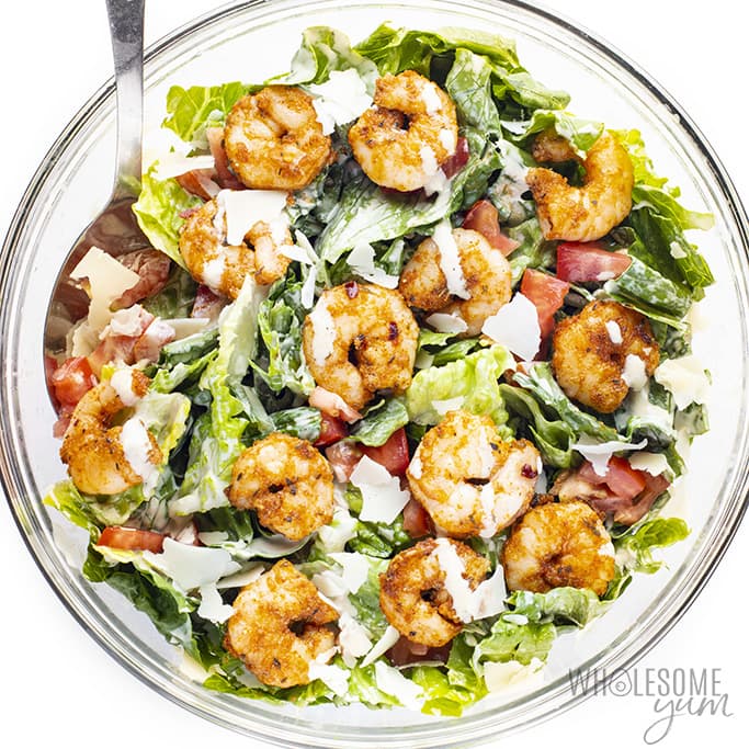 shrimp caesar salad recipe in a bowl with dressing