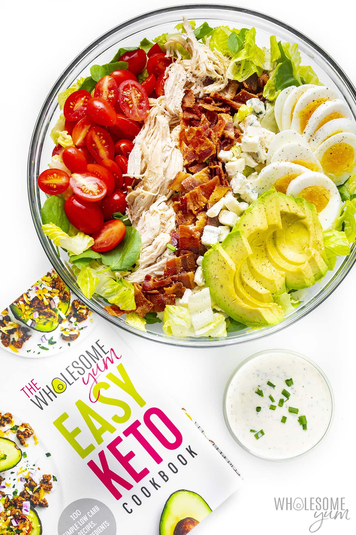 Cobb salad in a bowl next to cookbook.