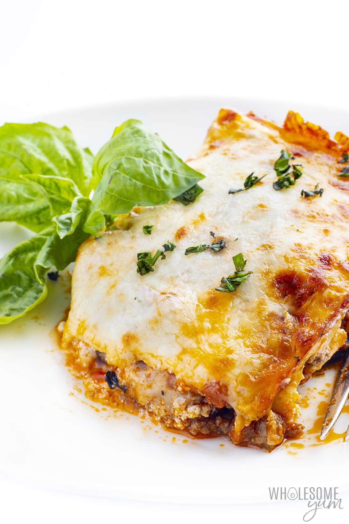 Slice of eggplant lasagna on a plate with fresh basil.